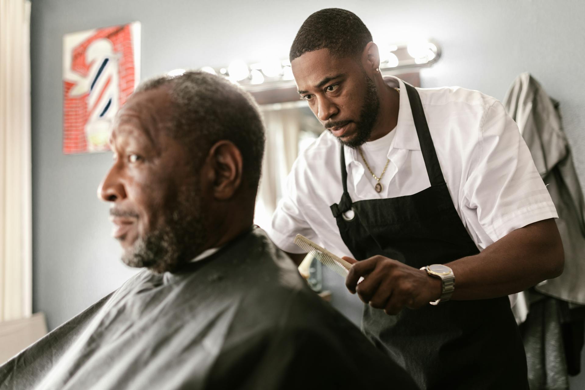 Barber attending to an elderly Black client